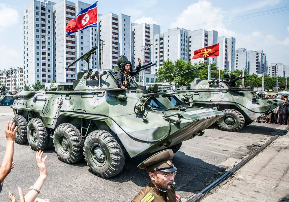Tranh treo tường chủ đề duyệt binh với xe bọc thép quân sự và cờ Triều Tiên giữa khu đô thị