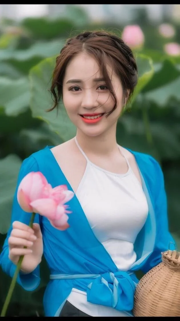 Gái đẹp Việt Nam mặc áo cardigan xanh cầm hoa sen hồng