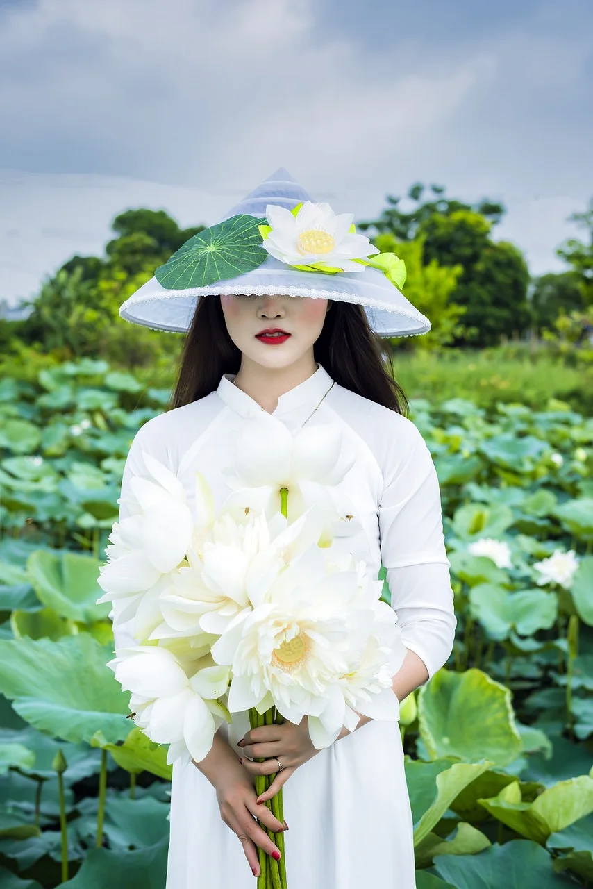 Gái đẹp Việt Nam mặc áo dài trắng đội nón lá cầm bó hoa sen trắng giữa bãi sen xanh