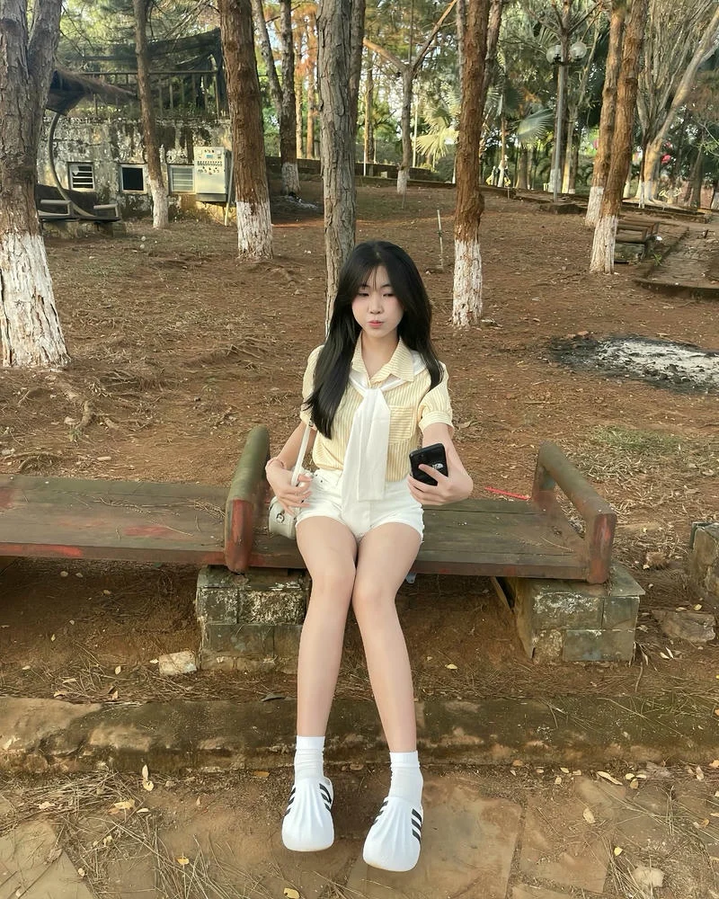 Gái đẹp Việt Nam ngồi trên ghế gỗ trong công viên