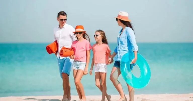 Ảnh đại diện đẹp về gia đình bốn người vui vẻ dạo bước trên bãi biển nhiệt đới với phao bơi xanh ngọc