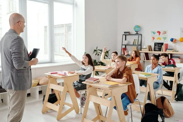 hình ảnh lớp học sôi nổi với thầy giáo và học sinh giơ tay phát biểu
