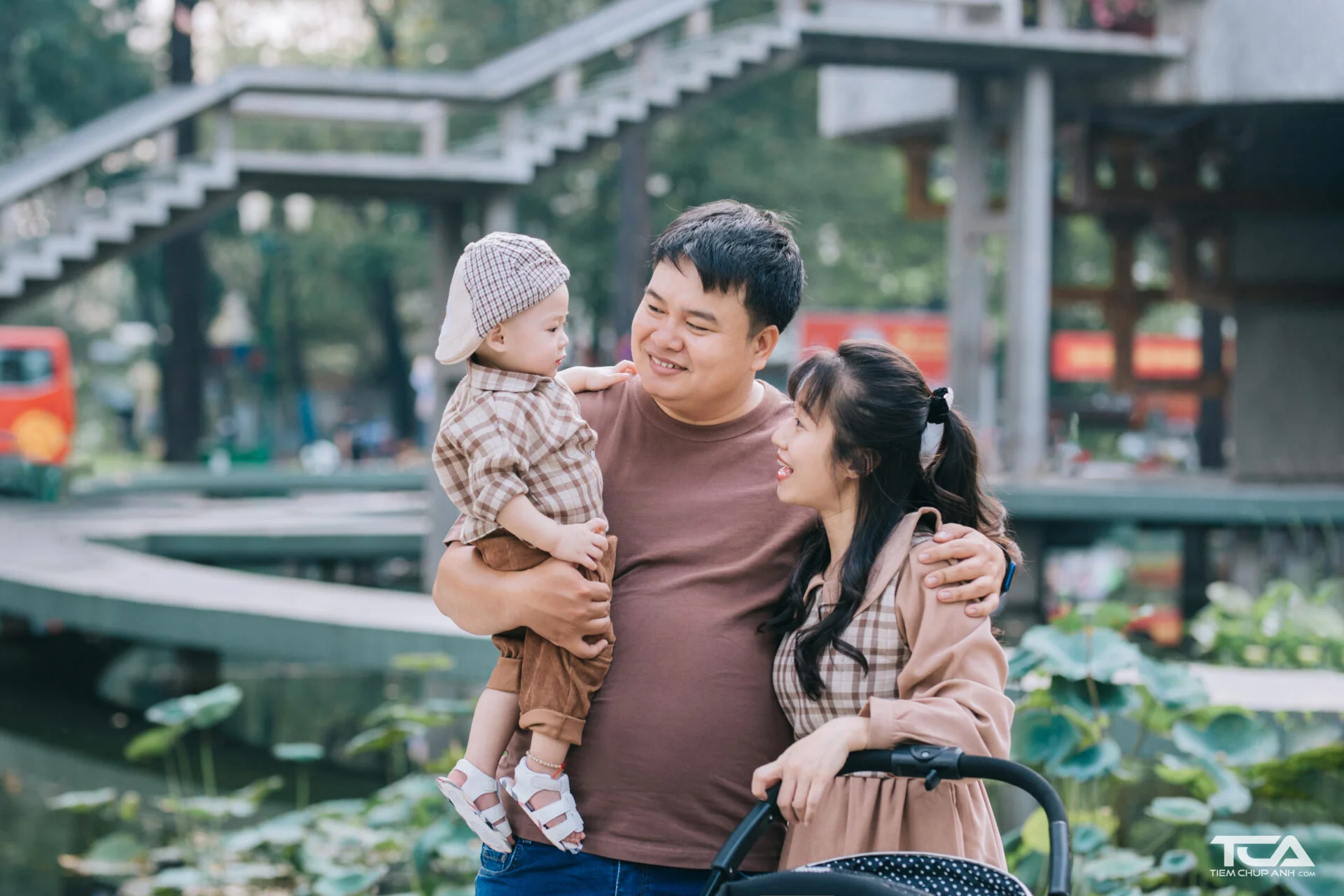 Hình ảnh gia đình hạnh phúc gồm bố mẹ và con nhỏ đang cùng nhau dạo chơi tại công viên.