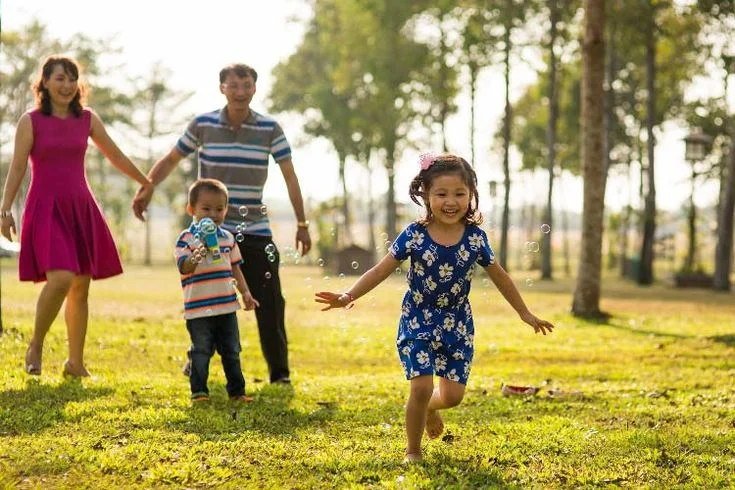 hình ảnh gia đình hạnh phúc đang vui chơi và thổi bong bóng ngoài công viên